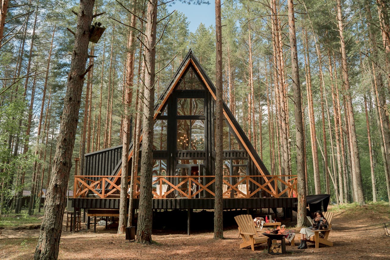 About A-frame cabin nestled among pine trees with outdoor seating, perfect for relaxation and nature getaways.